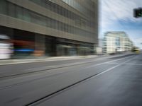 the motion blurs off a moving train on tracks in a big city street, and the buildings are also blurred