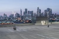 a parking lot in front of a city skyline at night time with buildings in the background