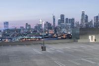 a parking lot in front of a city skyline at night time with buildings in the background