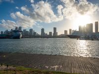 the view of a city in the sun with some palm trees next to the boardwalk