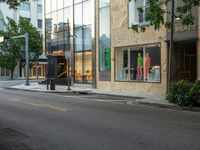 the store fronts and the trees are reflecting the windows of a city building as well