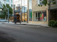 the store fronts and the trees are reflecting the windows of a city building as well