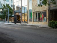 the store fronts and the trees are reflecting the windows of a city building as well