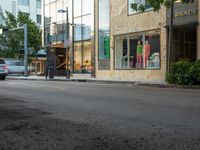 the store fronts and the trees are reflecting the windows of a city building as well