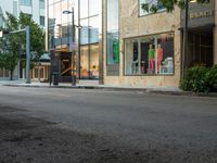 the store fronts and the trees are reflecting the windows of a city building as well