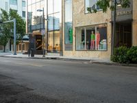 the store fronts and the trees are reflecting the windows of a city building as well