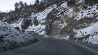 a car driving down a road in the snow on a mountain side cliff hill drive