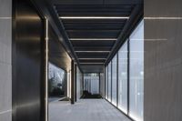 an empty walkway in a modern building with lots of glass windows, and a bench