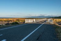 a fence with a white horse on top of it in the middle of the road