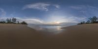 a panoramic view of the ocean from an empty beach with a boat and some trees in the background