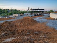 a picture of a building being built on a field near a forest in the background