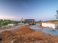 a picture of a building being built on a field near a forest in the background