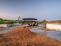 a picture of a building being built on a field near a forest in the background