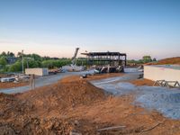 a picture of a building being built on a field near a forest in the background