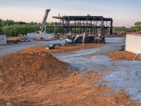 a picture of a building being built on a field near a forest in the background