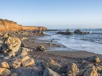 a grassy field by the shore and a cliff with rocks in the ocean in the background