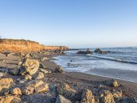 a grassy field by the shore and a cliff with rocks in the ocean in the background