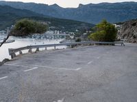 the view of a body of water with mountains in the background and parked cars parked next to the fence