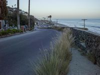 an empty road by the ocean at dusk near the beach shore line with several parked cars