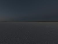 the dark sky above a desert plain with only one plane in sight in the distance