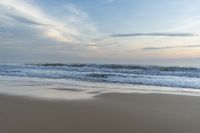 someone in the ocean at the beach watching the waves go by on the shore at sunset