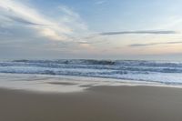 someone in the ocean at the beach watching the waves go by on the shore at sunset