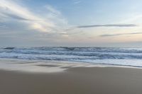 someone in the ocean at the beach watching the waves go by on the shore at sunset