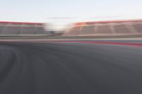 motion blurry shot on a racetrack, in a motion blurred scene, of a red racing car, moving down the track