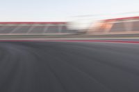 motion blurry shot on a racetrack, in a motion blurred scene, of a red racing car, moving down the track
