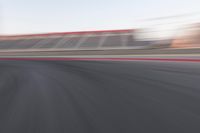 motion blurry shot on a racetrack, in a motion blurred scene, of a red racing car, moving down the track