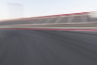 motion blurry shot on a racetrack, in a motion blurred scene, of a red racing car, moving down the track