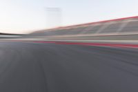 motion blurry shot on a racetrack, in a motion blurred scene, of a red racing car, moving down the track