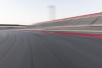 motion blurry shot on a racetrack, in a motion blurred scene, of a red racing car, moving down the track