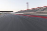motion blurry shot on a racetrack, in a motion blurred scene, of a red racing car, moving down the track