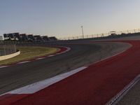 an empty race track with several buildings near by with a red and white border,