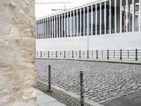 some black poles fence and a building with a white wall in the background on the street