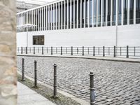 some black poles fence and a building with a white wall in the background on the street