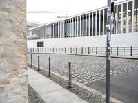 some black poles fence and a building with a white wall in the background on the street