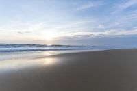 the ocean is blue and still calm as we walk along this beach, at dusk