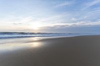 the ocean is blue and still calm as we walk along this beach, at dusk