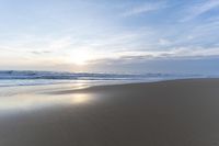 the ocean is blue and still calm as we walk along this beach, at dusk