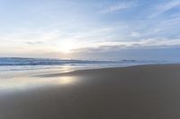 the ocean is blue and still calm as we walk along this beach, at dusk