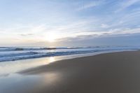 the ocean is blue and still calm as we walk along this beach, at dusk