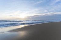 the ocean is blue and still calm as we walk along this beach, at dusk