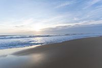 the ocean is blue and still calm as we walk along this beach, at dusk