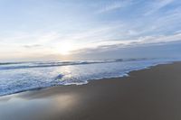 the ocean is blue and still calm as we walk along this beach, at dusk