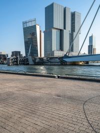 a sidewalk that is next to the water on a sunny day and has buildings in the background