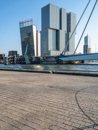 a sidewalk that is next to the water on a sunny day and has buildings in the background