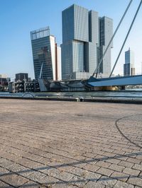 a sidewalk that is next to the water on a sunny day and has buildings in the background