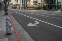 a fire hydrant is on the curb beside an empty street with buildings in the background